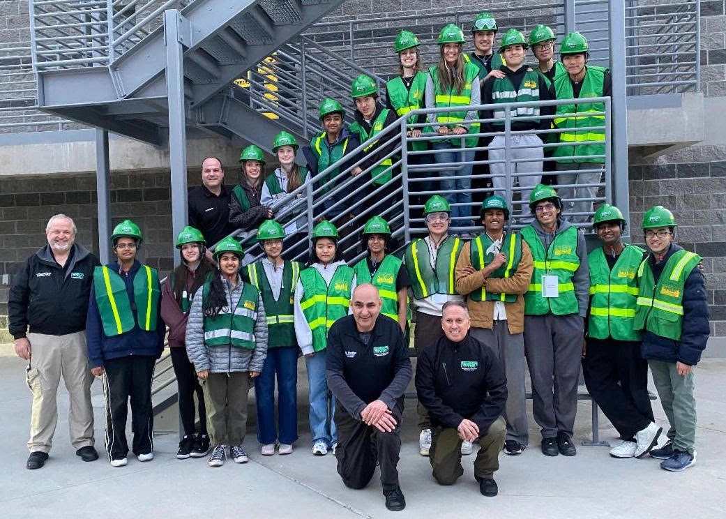 CERT participants and instructors in green helmets and safety vests gathered on an outdoor staircase